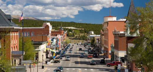 Leadville Main Street on a sunny day, with cars driving along the street and a clear backdrop.