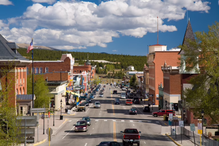Leadville Main Street on a sunny day, with cars driving along the street and a clear backdrop.