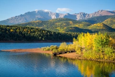 Mountain landscape with aspen trees and a lake or water body beneath it.