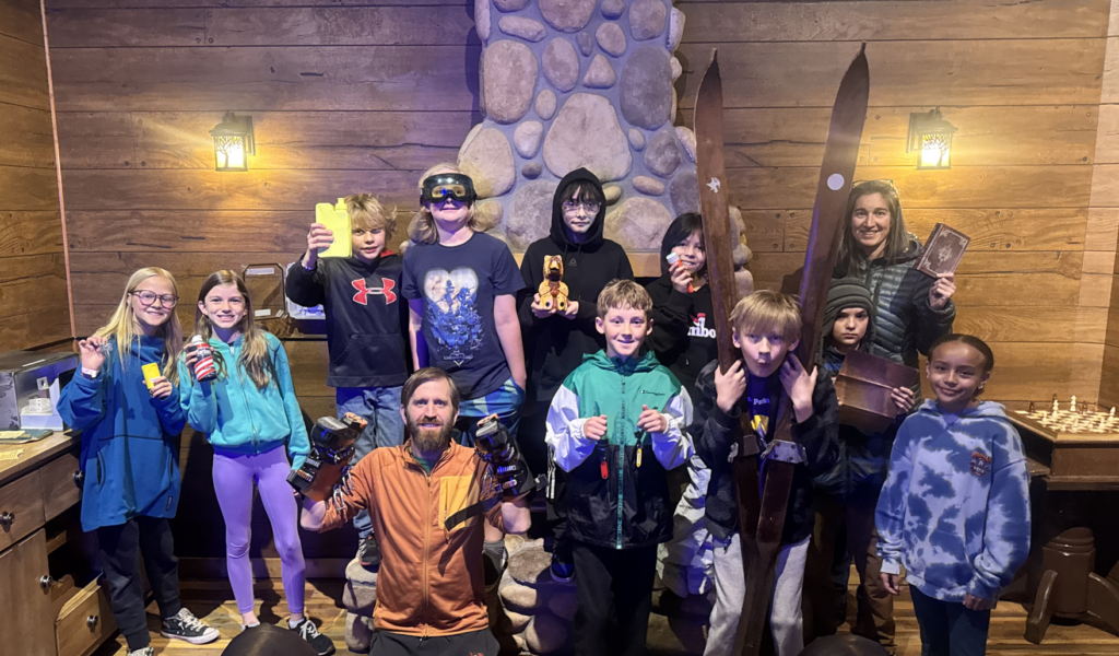 Students posing in a cabin where they participated in "Escape Room" activities.