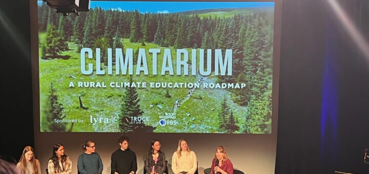 Students and teacher presenting the Climatarium Rural Climate Education Roadmap in front of a group in an auditorium